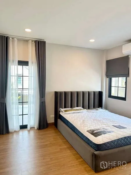 Detached House for rent in Bang Phli, Samut Prakan - Sunlit bedroom with upholstered bed, corner windows and blackout curtains.