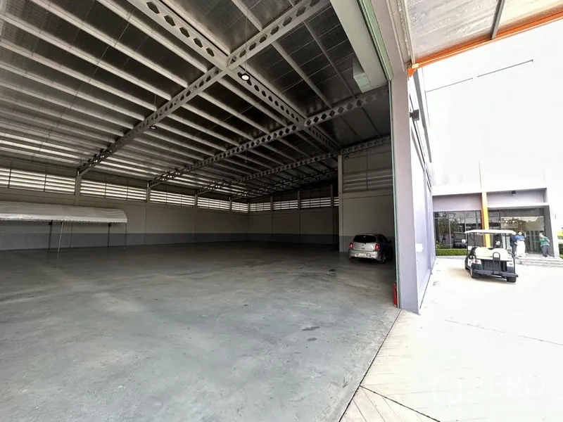 Factory for rent or sale in Lam Luk Ka, Pathum Thani - Spacious high-ceiling factory floor with steel trusses and polished concrete, viewed from the loading door.