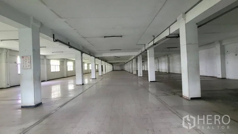Factory for rent in Mueang Samut Prakan, Samut Prakan - Deep production area with continuous columns and fluorescent lighting