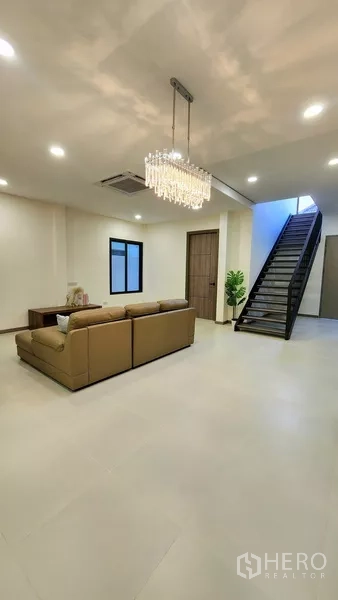 独立式住宅 出售在Khlong Toei, Bangkok - 宽敞客厅，水晶吊灯、沙发与开放式金属楼梯。