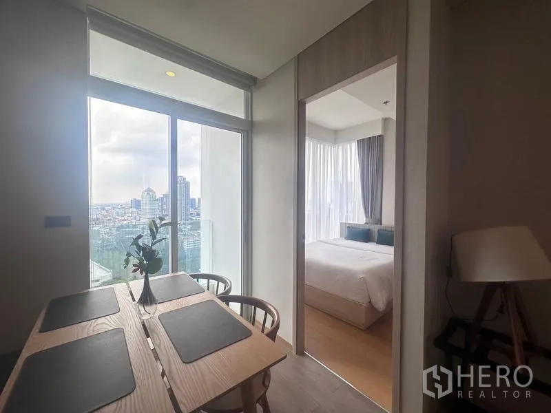 Condominium for rent - Dining area by full-height glass doors with city view and doorway to bedroom.