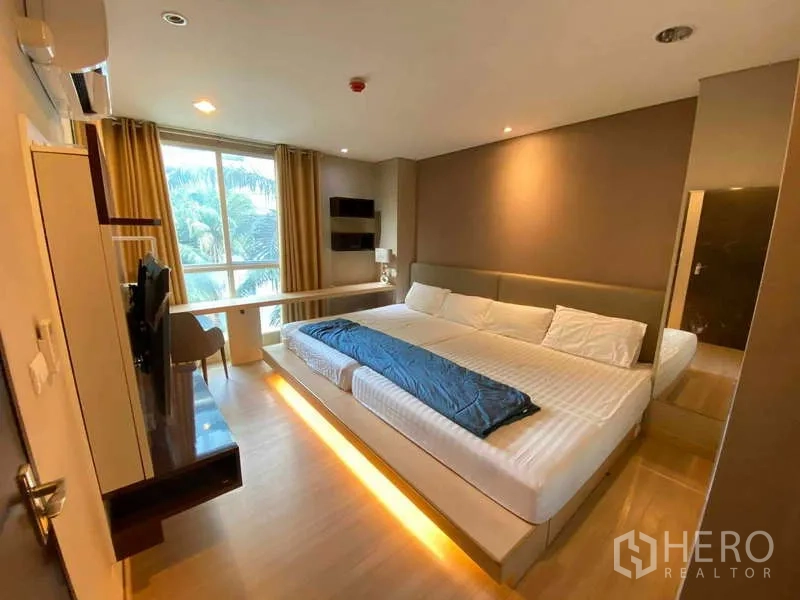 公寓 出租在Ratchathewi, Bangkok - 主卧配特大床、电视柜、书桌与大窗，可见绿意景观。