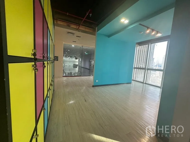 办公空间 出租在Bang Rak, Bangkok - 入口区设置多彩员工柜与蓝色休闲角，旁为落地玻璃。