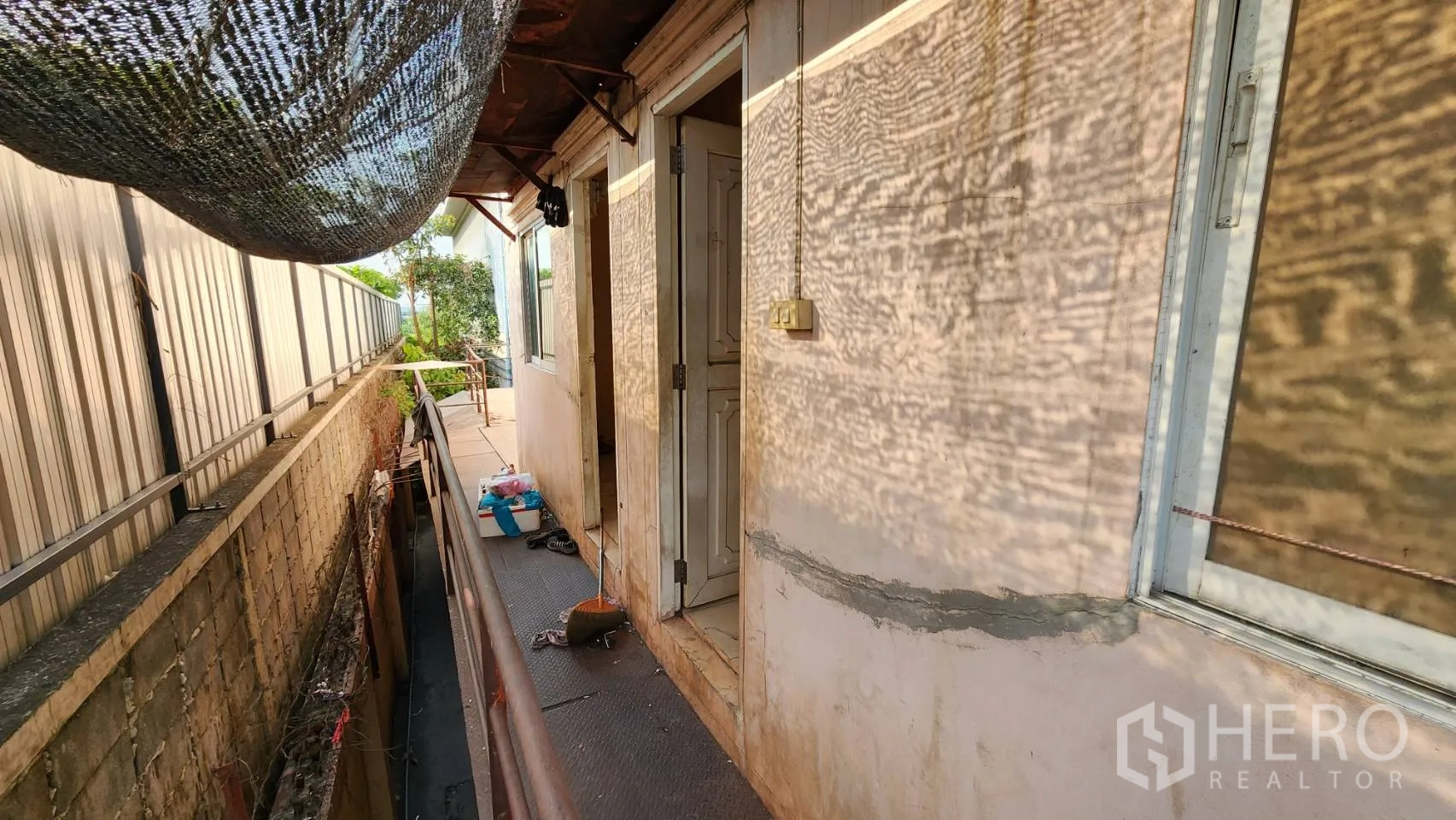 Warehouse for rent in Nonthaburi - Rear service walkway with canopy netting beside the boundary wall.
