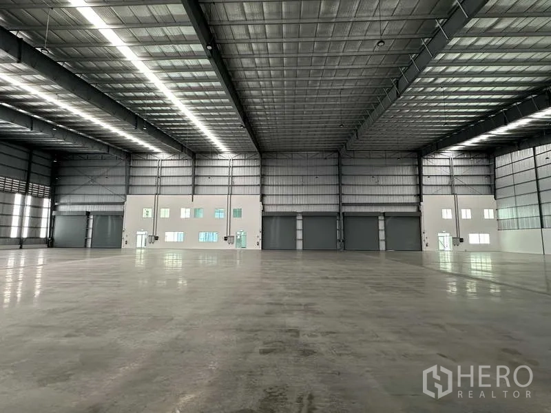 Factory for rent in Bang Sao Thong, Samut Prakan - Spacious warehouse interior with polished floor, 8 m clear height, and skylit steel roof.