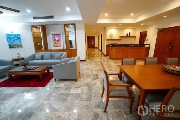 Apartment for rent in Watthana, Bangkok - Bright lounge with gray sofas, wall art and a dining corner beside a built-in bar counter.