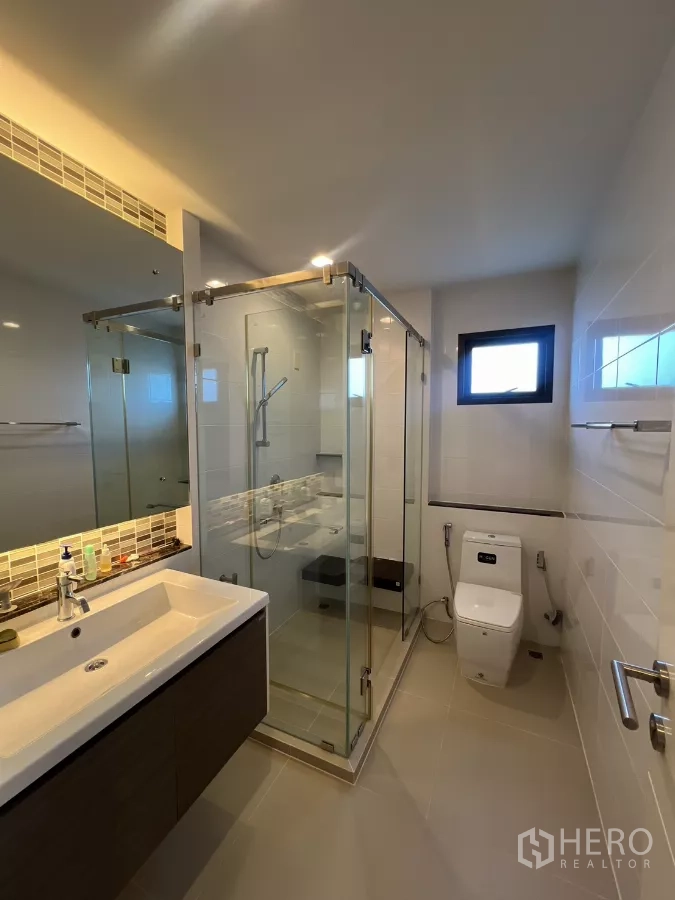 Detached House for rent in Bang Kapi, Bangkok - Master bathroom with glass-enclosed shower, vanity, and toilet.