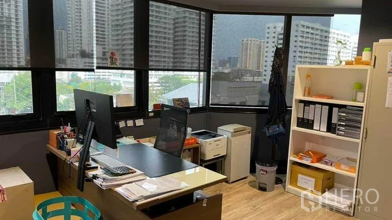 Office Space for rent in Khlong Toei, Bangkok - Manager’s corner desk facing wraparound windows with city views and shelving.