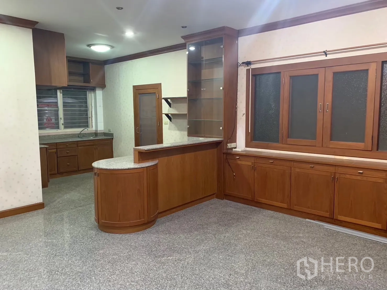 Detached House for rent in Watthana, Bangkok - Open kitchen and pantry with extensive wooden cabinetry and glass shelves.