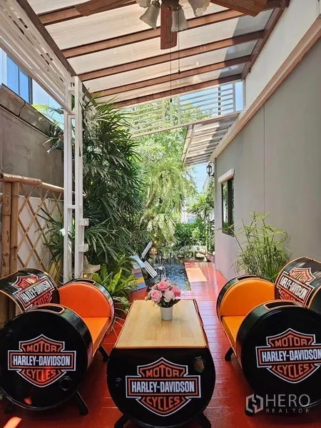 Townhouse for rent - Covered patio lounge with ceiling fan, barrel-style seating and lush greenery.