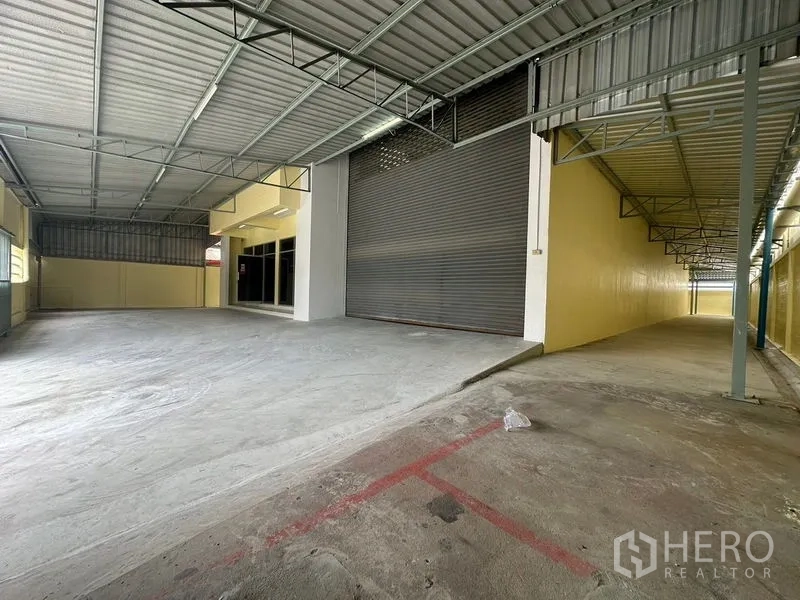 Factory for rent in Pathum Thani - Covered loading bay with high roller shutter and wide driveway access.