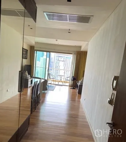 Condominium for rent in Khlong Toei, Bangkok - Open-plan living and dining area with wood floors leading to a balcony with city views.
