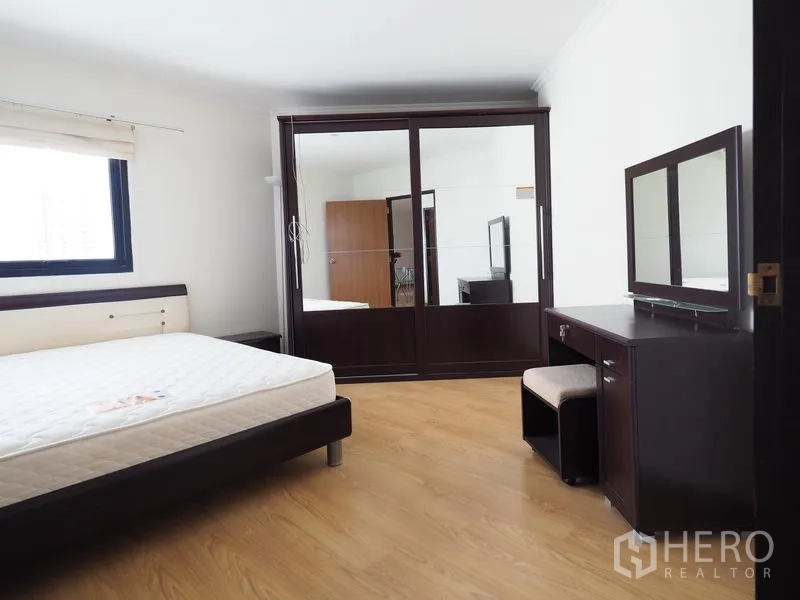 Condominium for rent in Sathon, Bangkok - Bedroom with sliding mirror wardrobe, dressing table and bed frame on wood floors.