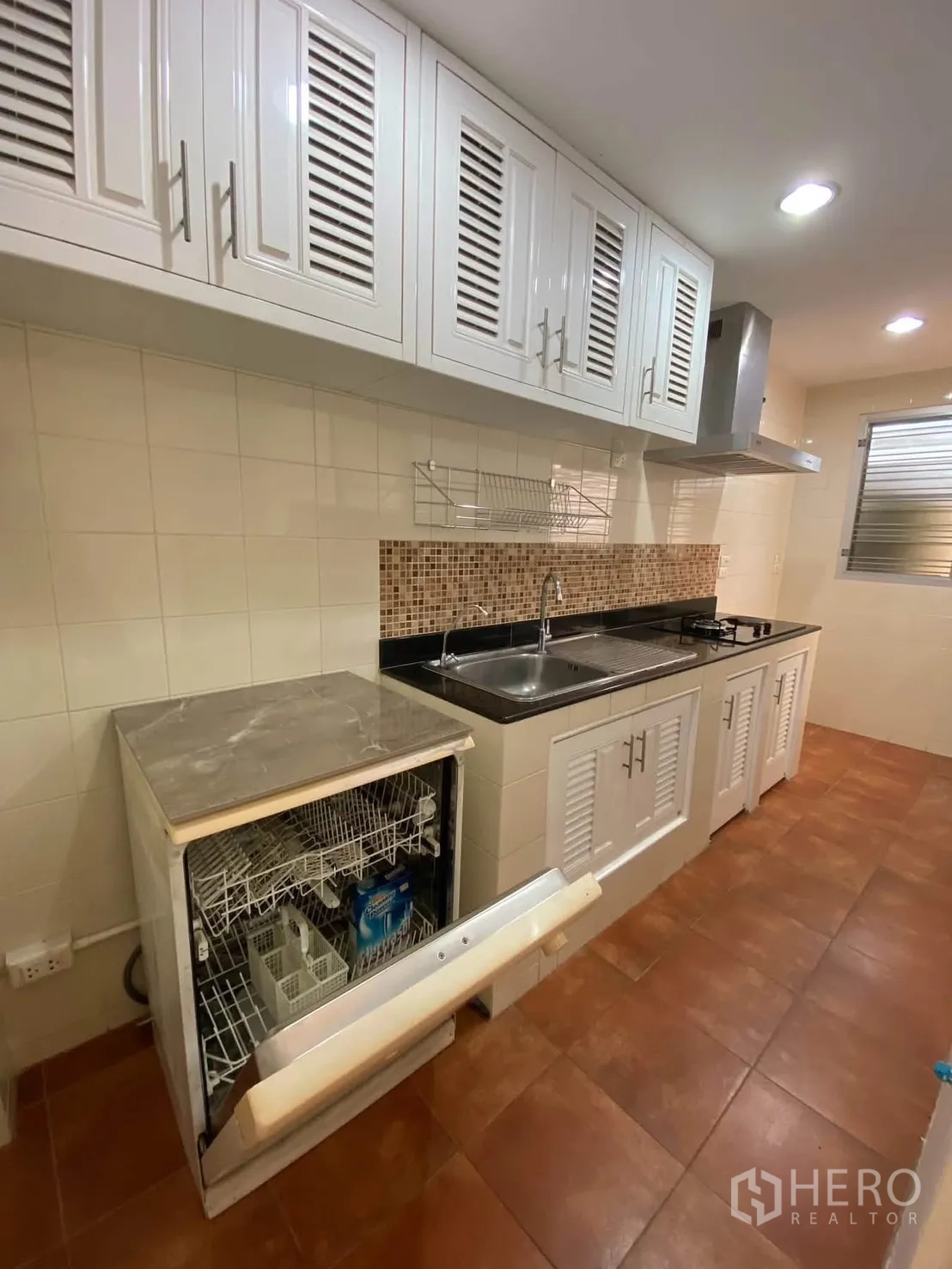 独栋房屋 for rent in Mueang Samut Prakan, Samut Prakan - 嵌入式厨房，白色橱柜、炉灶、油烟机与打开的洗碗机。