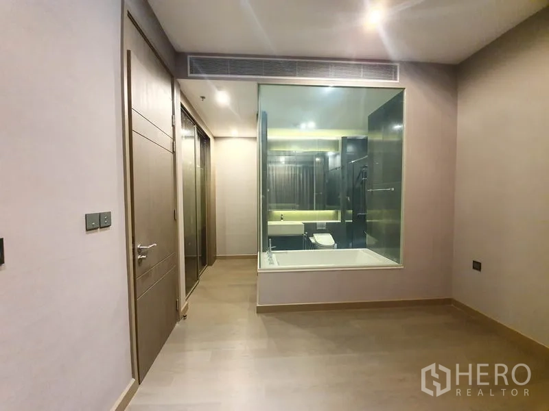 คอนโด ให้เช่าในHuai Khwang, Bangkok - มุมมองจากห้องนอนไปยังห้องน้ำผ่านผนังกระจก พื้นไม้และไฟฝังเพดาน