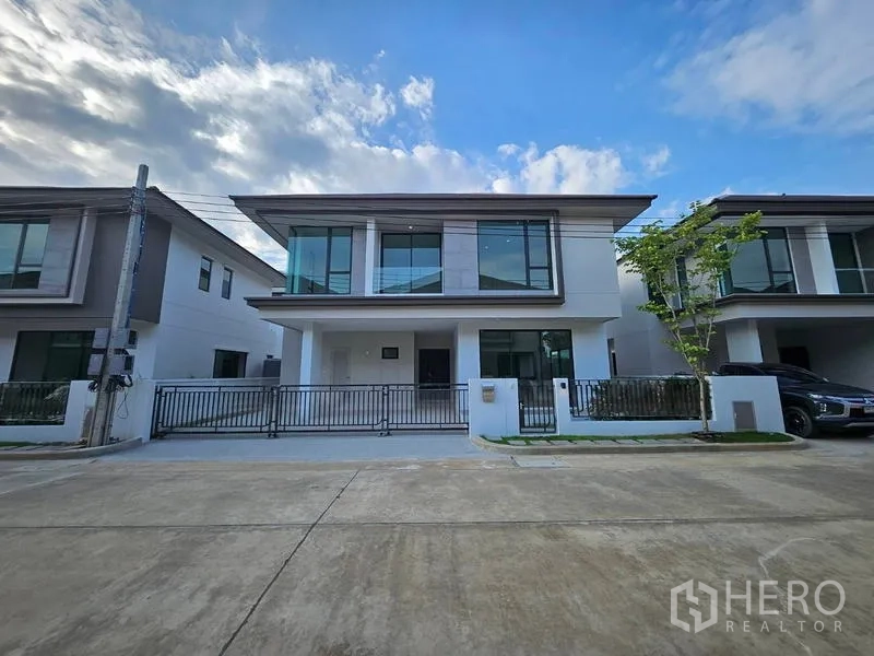Detached House for rent in Saphan Sung, Bangkok - Street view of a contemporary two-storey home with front gate and small tree.