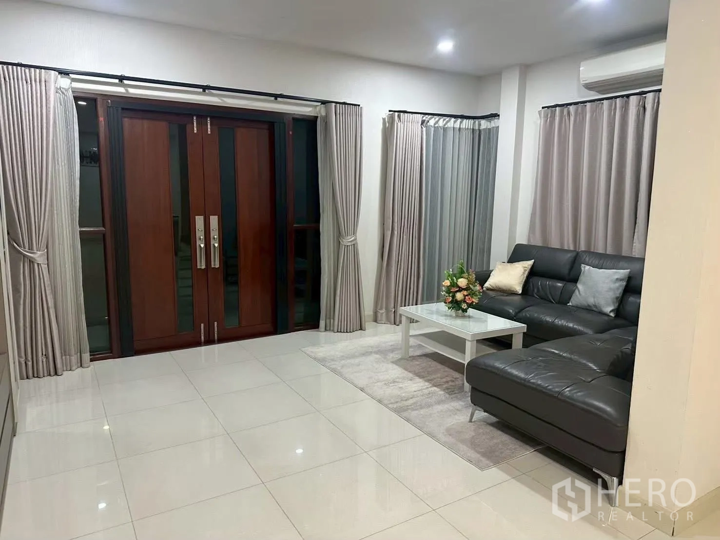 Detached House for rent in Bang Phli, Samut Prakan - Bright living room with L-shaped leather sofa, coffee table and wooden double doors.