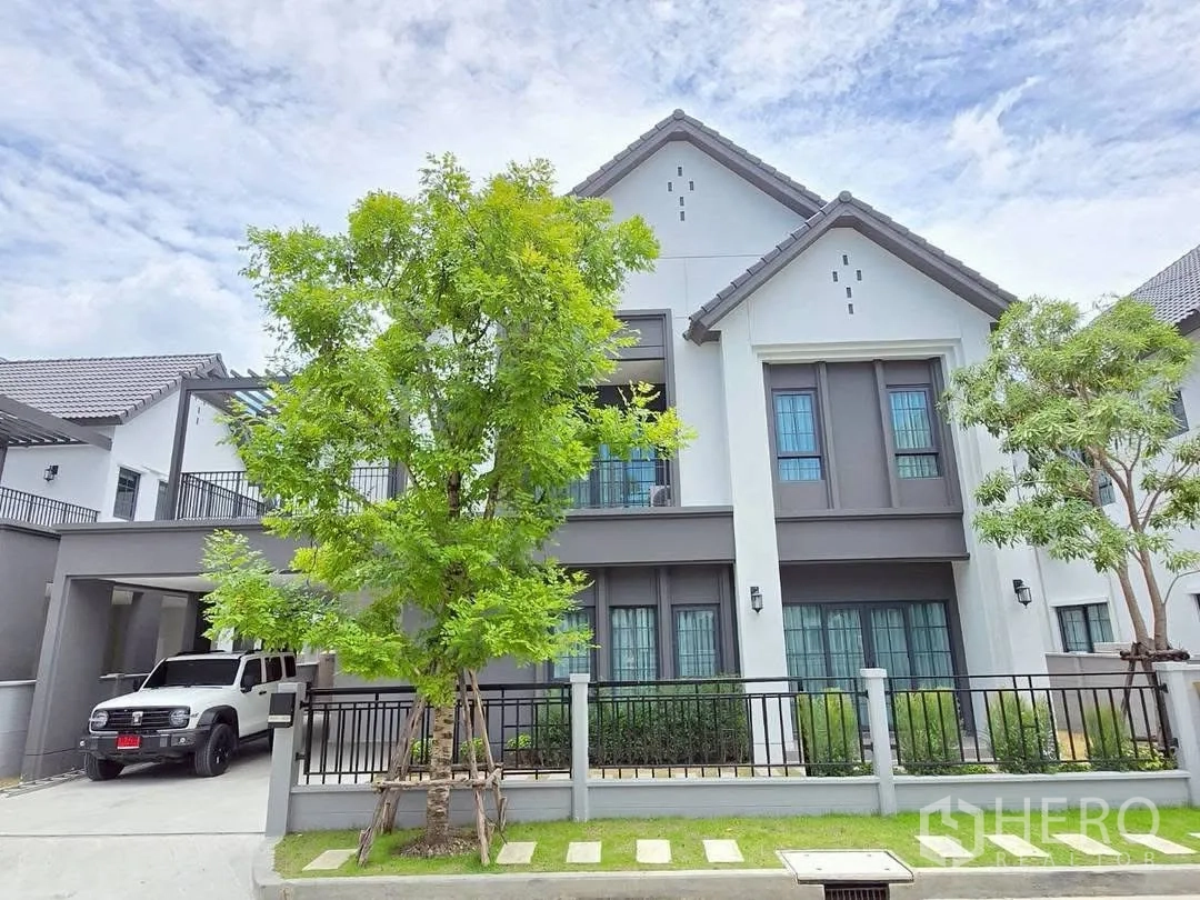 Detached House for rent in Bang Phli, Samut Prakan - Contemporary two-storey house exterior with gated driveway, carport, and mature trees.
