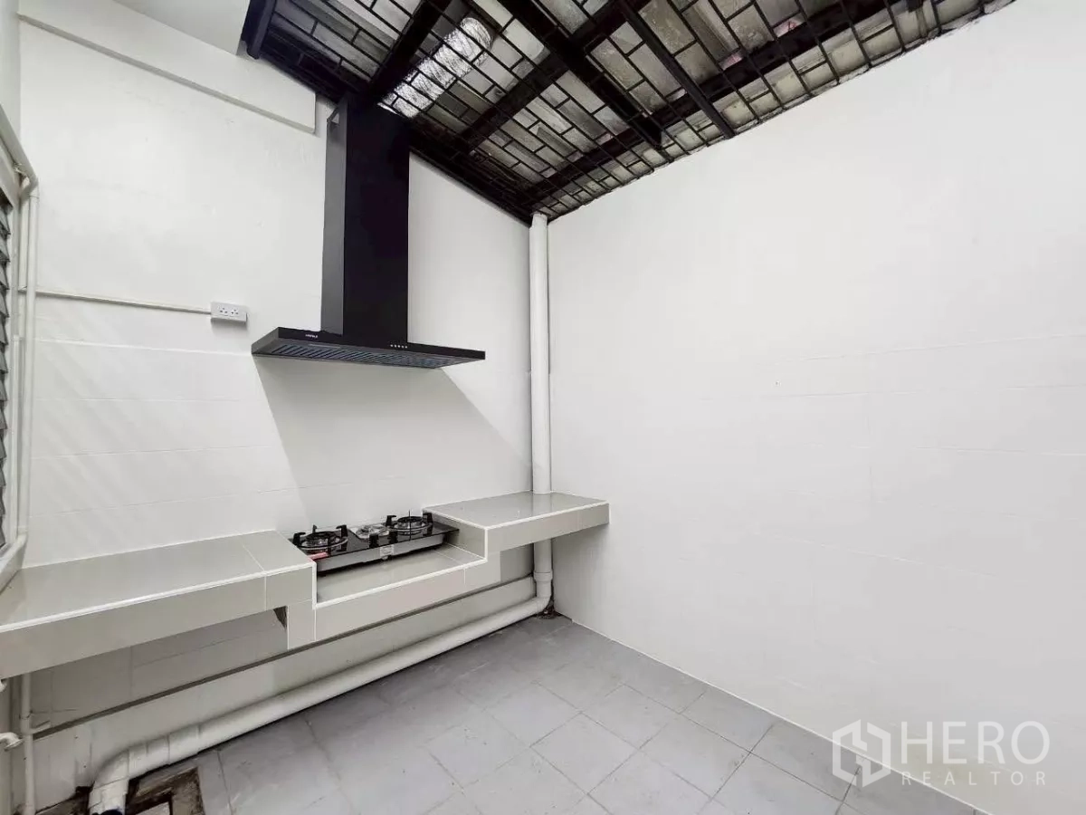 Townhouse for rent in Huai Khwang, Bangkok - Thai kitchen with gas stove, range hood and easy-clean counters under a metal grid roof.
