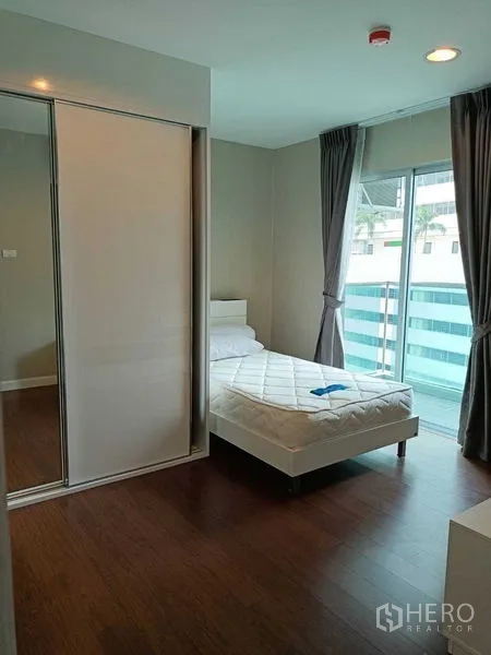 คอนโด ให้เช่าหรือขายในHuai Khwang, Bangkok - ห้องนอนมีตู้เสื้อผ้าบานเลื่อนและทางออกสู่ระเบียงผ่านประตูกระจก.