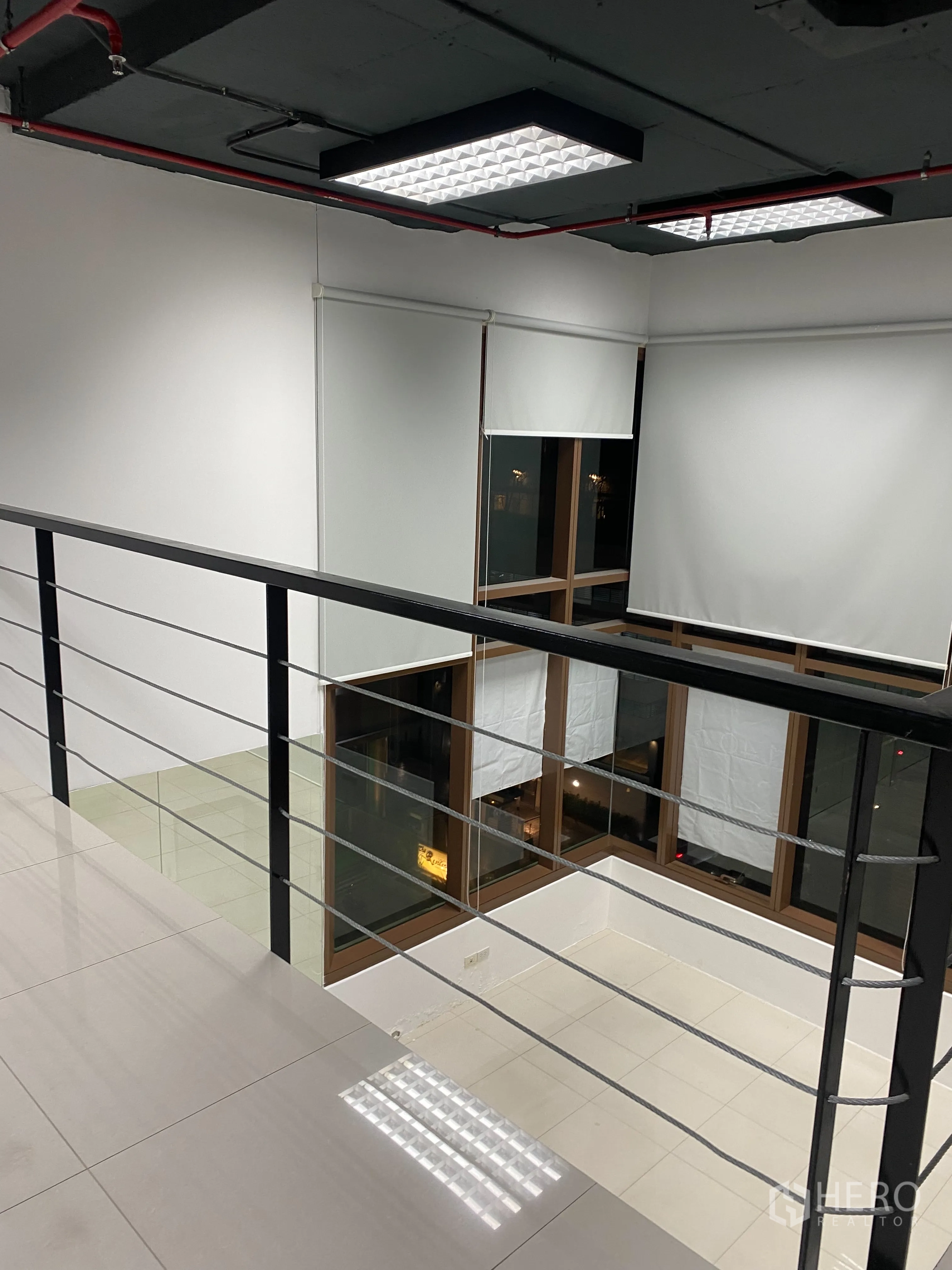 Office Space for rent in Khlong Toei, Bangkok - Evening view from the mezzanine with metal railing looking over tall corner windows.