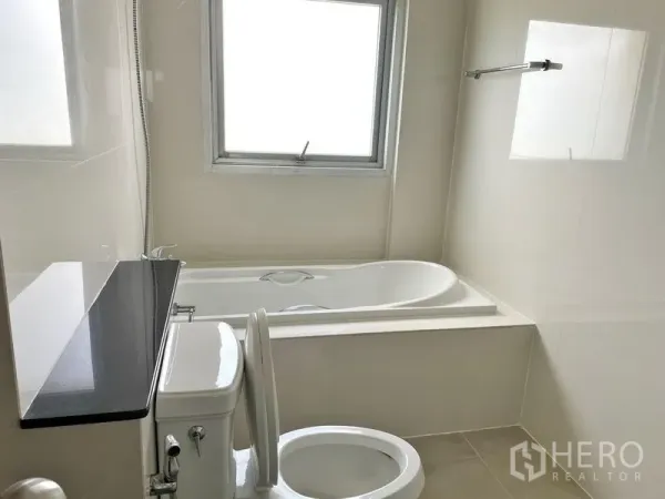 Condominium for rent in Khlong Toei, Bangkok - Clean bathroom with bathtub, shower handset, window and toilet.