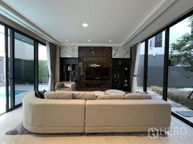 Detached House for rent in Suan Luang, Bangkok - Family room with built‑in TV wall and glass doors to the pool and courtyard.