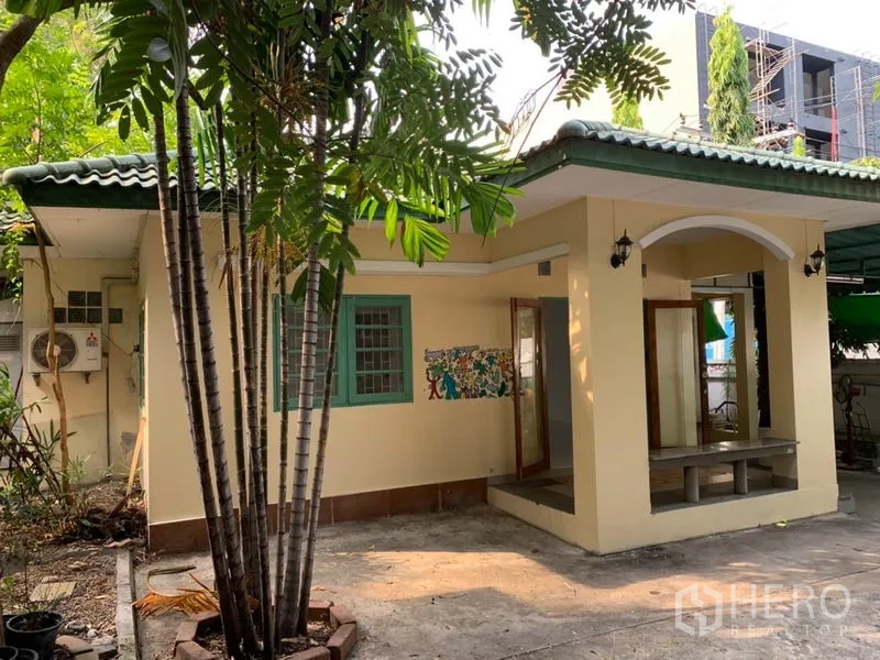 独立式住宅 出租在Khlong Toei, Bangkok - 房屋侧景，可见棕榈树、小露台与车道。