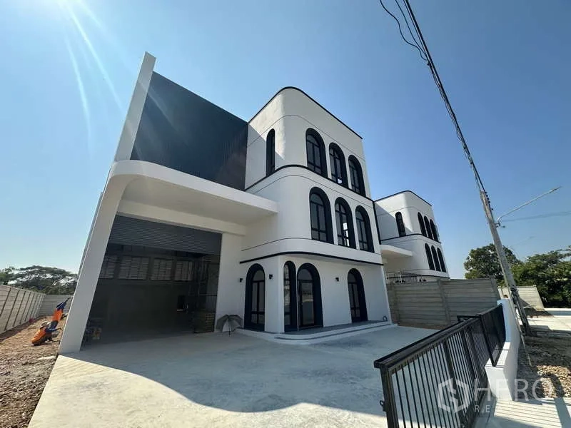 工厂 出售在Lam Luk Ka, Pathum Thani - 现代工厂立面，带有室内装卸区、大型卷帘门和办公区。