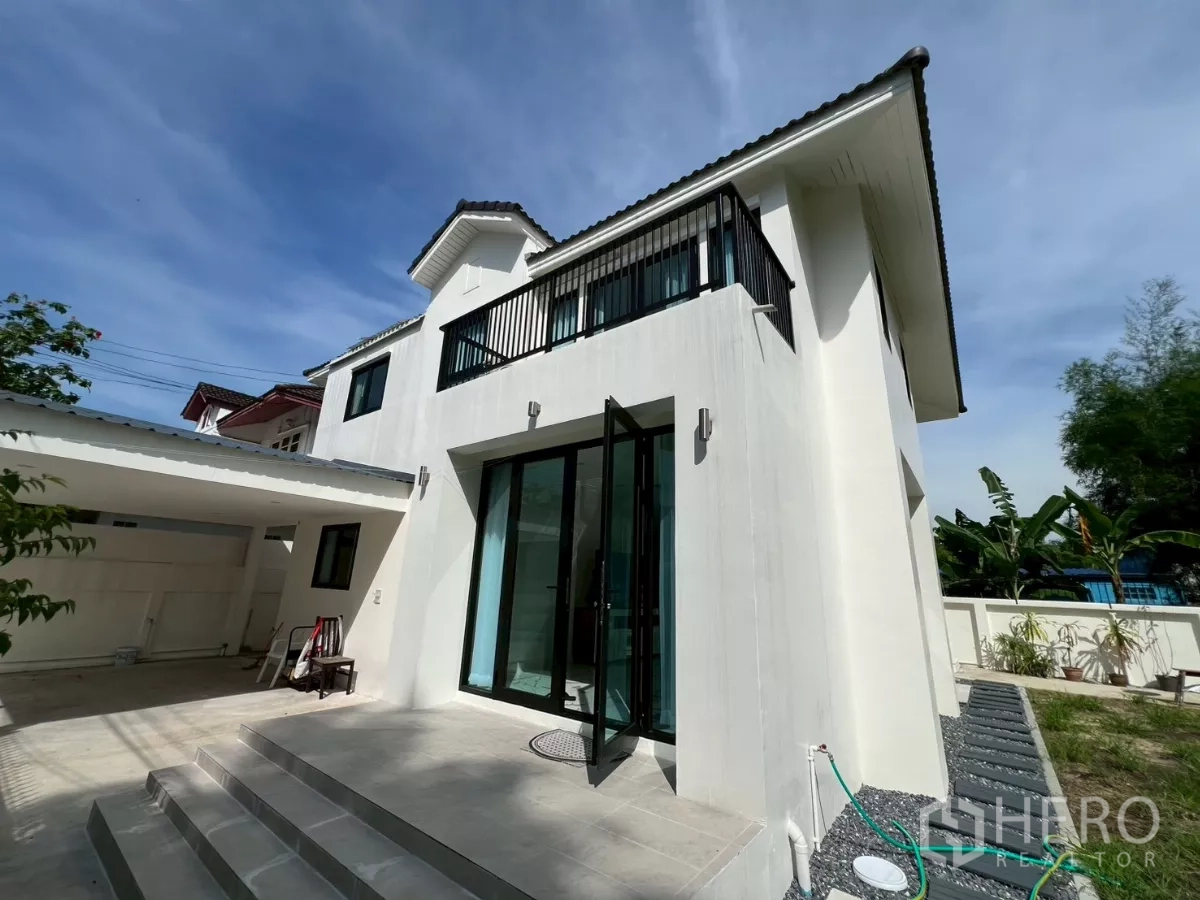 独立式住宅 出租在Suan Luang, Bangkok - 前露台与阳台视角，外墙新刷白色并配有有顶停车位。