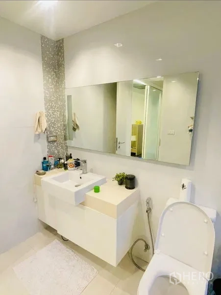 Condominium for rent or sale in Sathon, Bangkok - Clean bathroom with white vanity, mosaic accent strip and wall mirror.
