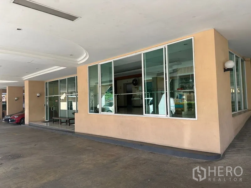 Office Space for sale - Covered driveway and glass-fronted lobby of an office building in Bangkok.