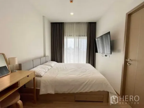 公寓 出租或出售在Watthana, Bangkok - 极简卧室，纱帘与壁挂电视，自然光柔和。