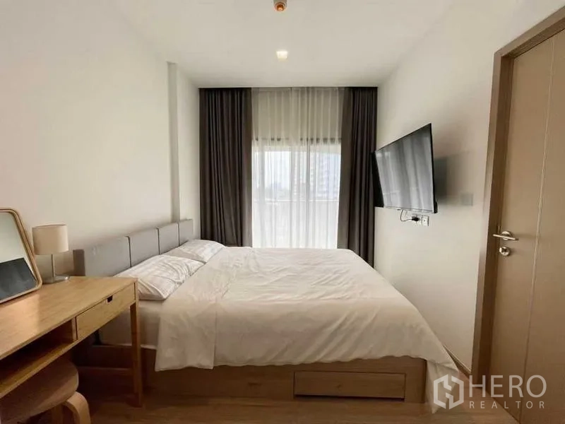 公寓 出租或出售在Watthana, Bangkok - 极简卧室，纱帘与壁挂电视，自然光柔和。