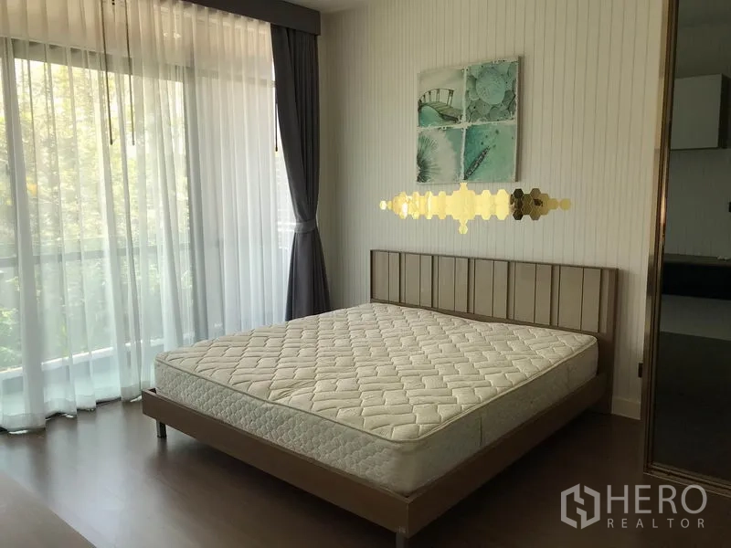 Detached House for rent in Bang Kapi, Bangkok - Master bedroom with full-height windows, sheer curtains, wood flooring and bed frame.