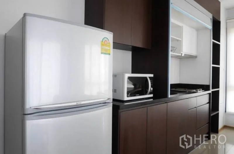 Condominium for rent in Phaya Thai, Bangkok - Modern one-wall kitchen with dark cabinets, refrigerator, microwave and cooktop.