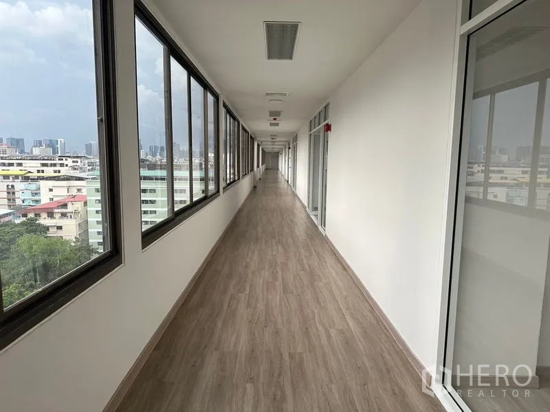 Office Space for rent - Long corridor with windows and glass partitions, overlooking buildings in Din Daeng.