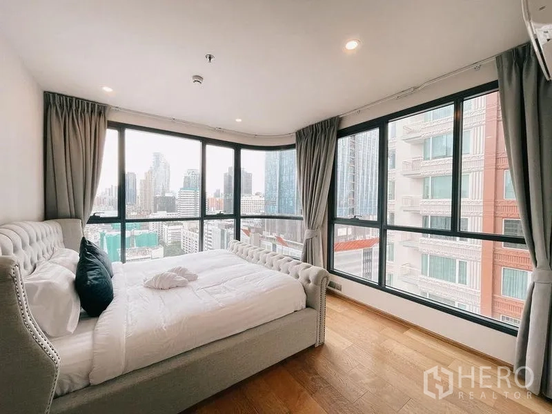 Condominium for rent in Ratchathewi, Bangkok - Corner master bedroom with panoramic windows and Bangkok skyline views.