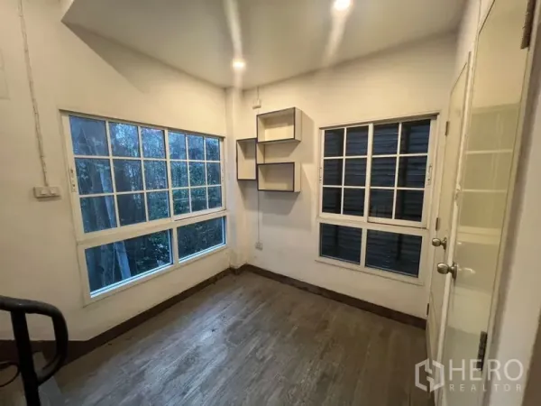 Shophouse for rent or sale in Watthana, Bangkok - Bright corner room with large grid windows, recessed lights and wall shelves.
