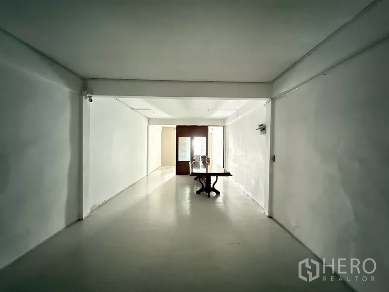 Shophouse for rent - Bright white room with a table leading to glass doors at the far end.