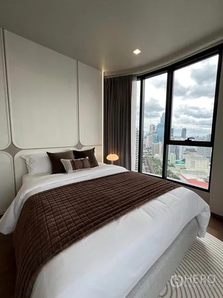 公寓 出租在Ratchathewi, Bangkok - 温馨卧室，绗缝被与转角高窗框景城市。