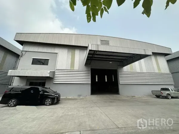 Warehouse for rent in Bang Phli, Samut Prakan - Front view of the warehouse showing a large roller shutter entry and an attached office block under a canopy.