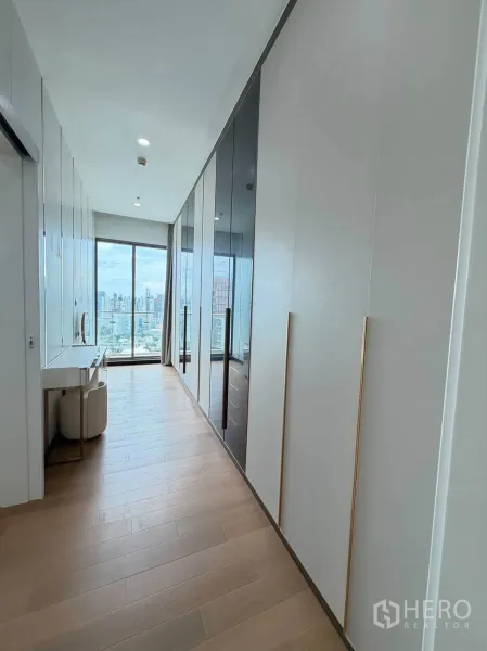 Condominium for sale in Watthana, Bangkok - Long dressing corridor with built-in wardrobes and makeup desk facing city views.