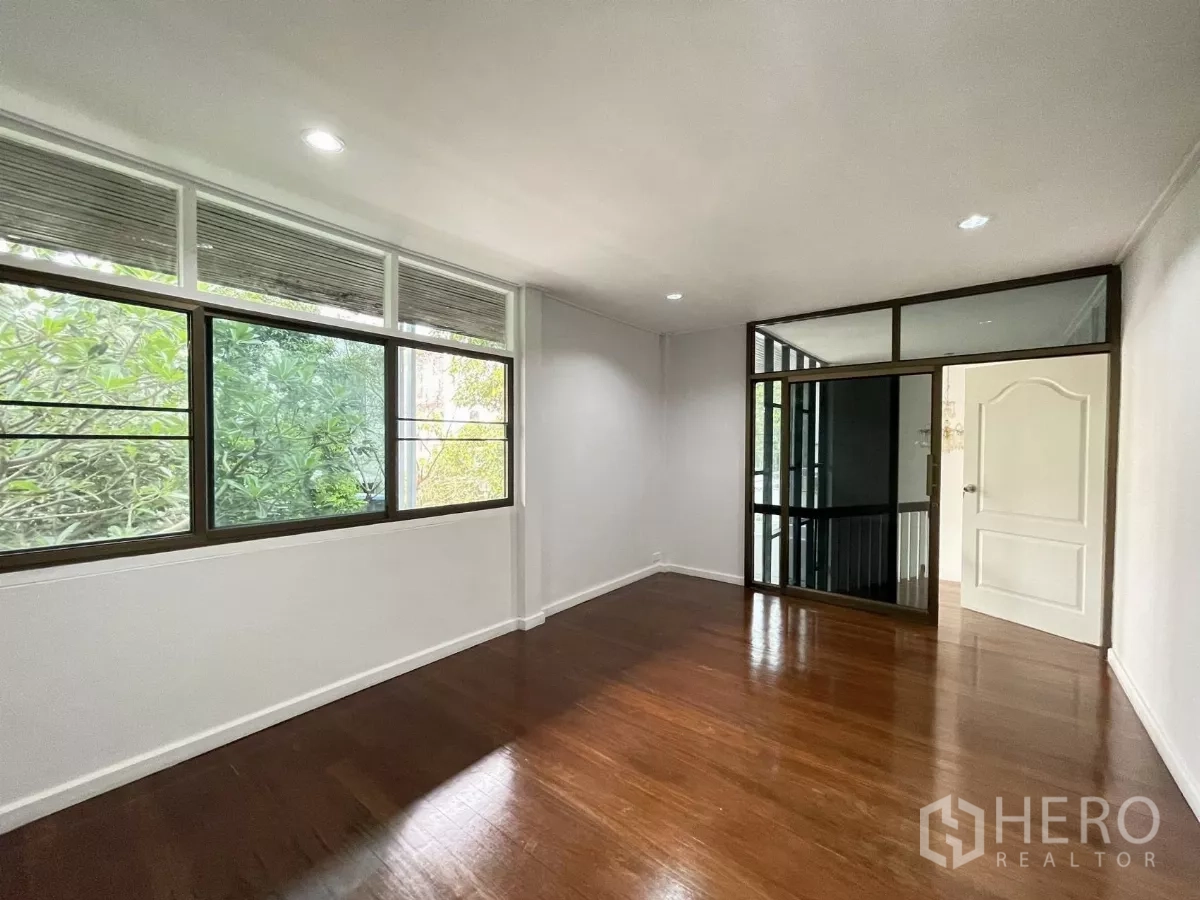 Home Office for rent in Din Daeng, Bangkok - Upper‑level room with wood flooring, sliding glass partition and wide garden‑view windows.