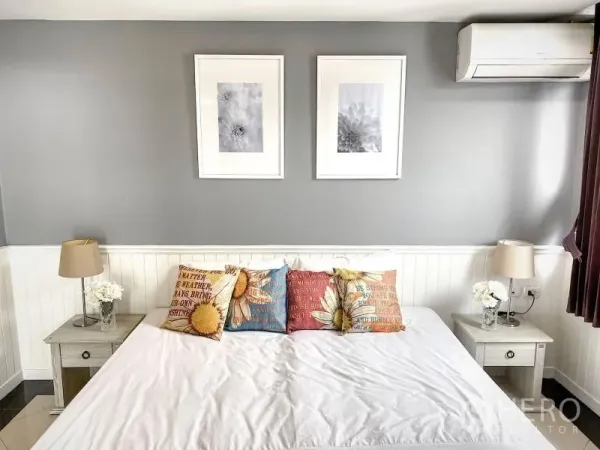 Condominium for rent in Khlong Toei, Bangkok - Cozy bedroom with gray accent wall, large bed, colorful pillows, lamps and air conditioner.