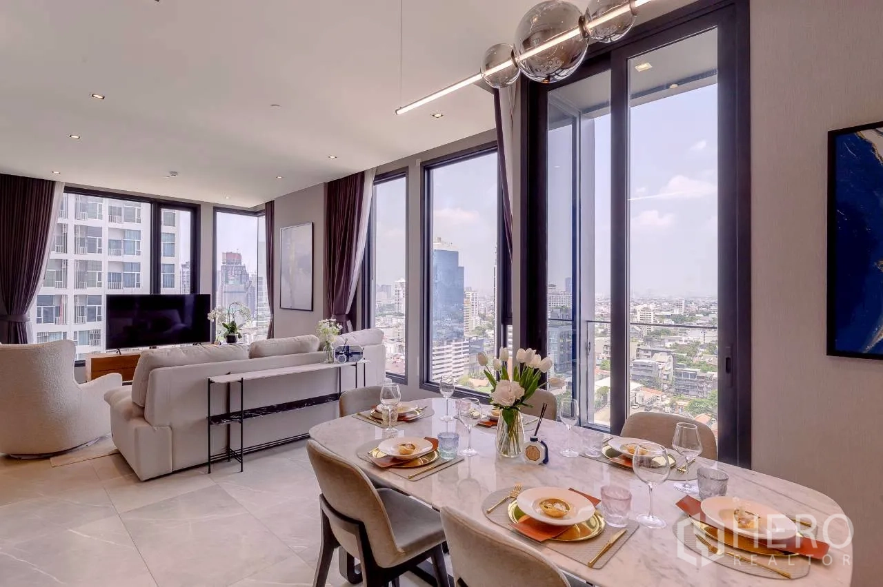 คอนโด for rent or sale in Watthana, Bangkok - พื้นที่นั่งเล่นและรับประทานอาหารแบบโอเพนแพลน พร้อมโต๊ะหินอ่อน โคมไฟแขวนสมัยใหม่ และหน้าต่างกระจกเต็มบานชมวิวเมือง
