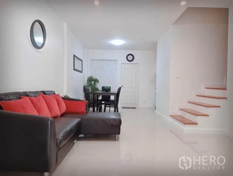 Townhouse for rent in Suan Luang, Bangkok - Living room angle showing staircase, dining table and L-shaped sofa