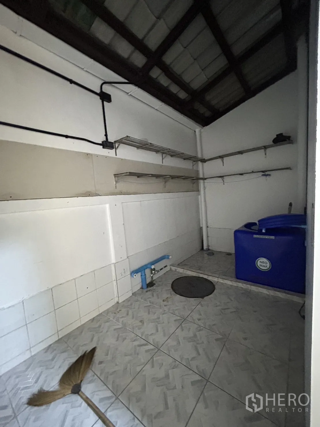 Shophouse for rent in Khlong Toei, Bangkok - Utility room with shelving, exposed piping, and a blue water tank.
