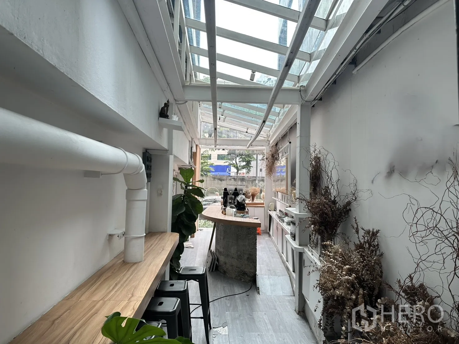 Retail Space for rent in Bang Rak, Bangkok - Glass-roofed corridor with a wooden bar counter, stools and greenery along the wall.