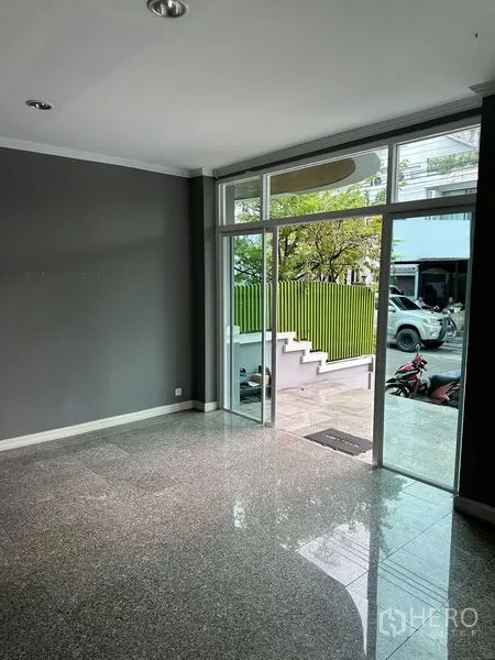 Townhouse for rent in Bang Kapi, Bangkok - Ground-floor lobby with full-height glass entrance doors overlooking front steps and a green fence.
